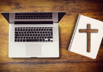 a picture of a cross on a notebook next to a laptop